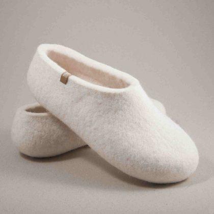 A pair of white wool slippers, clog style, for indoor use seen from the side, one rested upon the other.