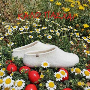 A pair of white wool slippers by Wooppers set on a wild flowers and daisies and scattered Easter eggs