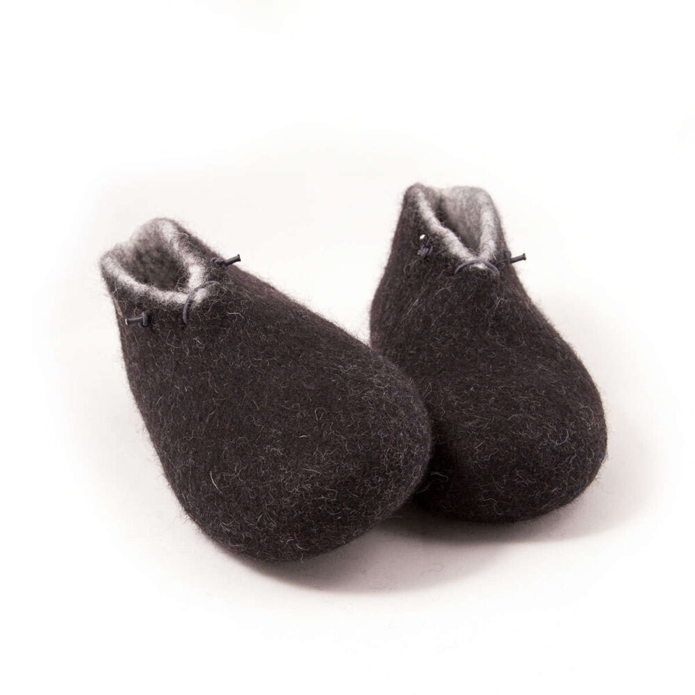 BOOTIE black white-e A pair of felted wool black booties for indoors use. The interior is white. They feature a leather tag on the side of the right shoe and tie elastic laces. Front view.
