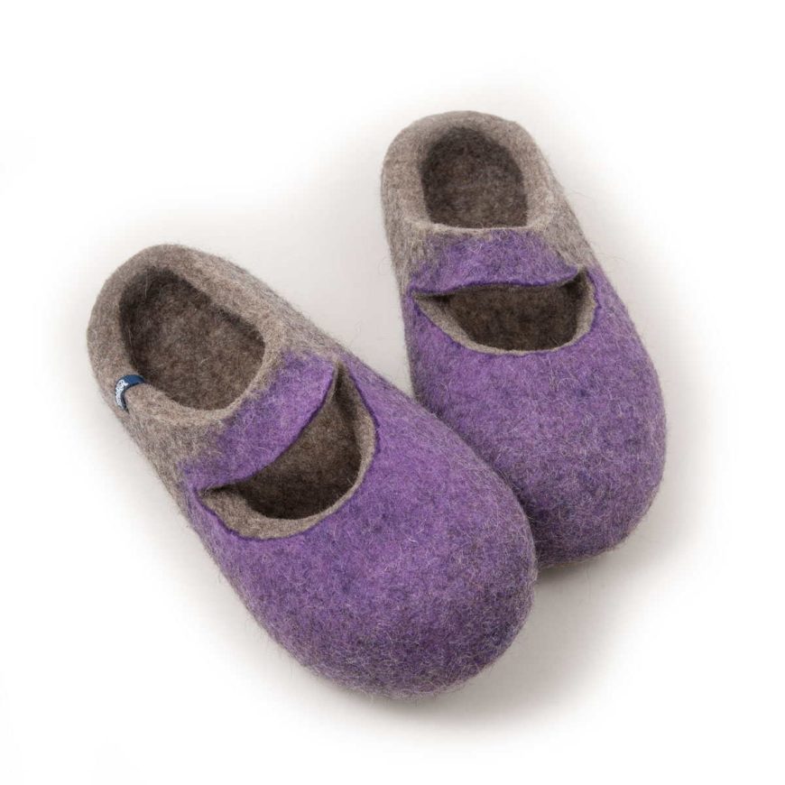 A pair of grey wool slippers with lilac on their front part. The slippers are felted without any seams. There is a cutout piece of the slipper where the ball of the foot is, leaving an opening in the shape of a smile.