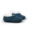 Side view of slippers in wool from the Colori collection by Wooppers. The slippers are felted in white and petrol blue wool and are cut either high or low at the back according to customer's taste. This pair is cut high at the back..
