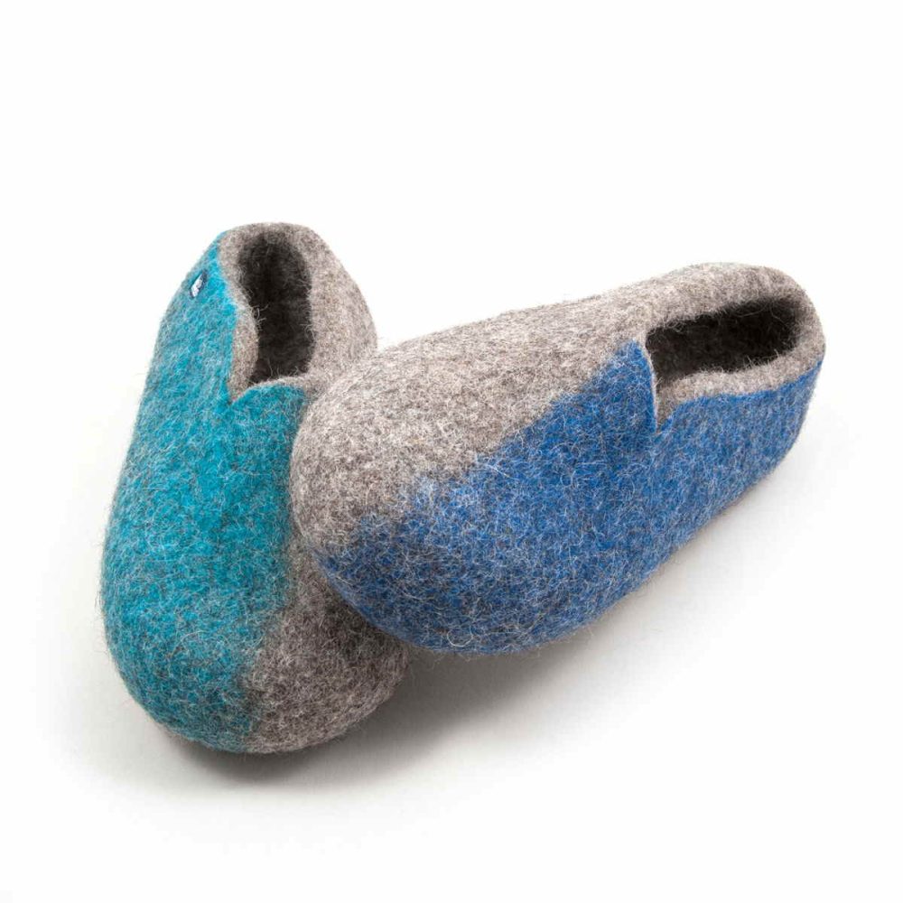 Slippers from the SEASONS collection by Wooppers. They are made of grey wool with colors on the outer side of the shoe. The left shoe with blue on the side rests on the right one with turquoise on its side.
