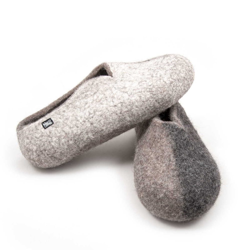 Winter - pure natural slippers from the SEASONS collection by Wooppers. The shoes are felted in grey wool with a stylish cut at the opening and different colors on the side of each shoe - white for the right and black for the left. The slippers are photographed with the right shoe over the left one.We can see the right on its side and the left in front view.