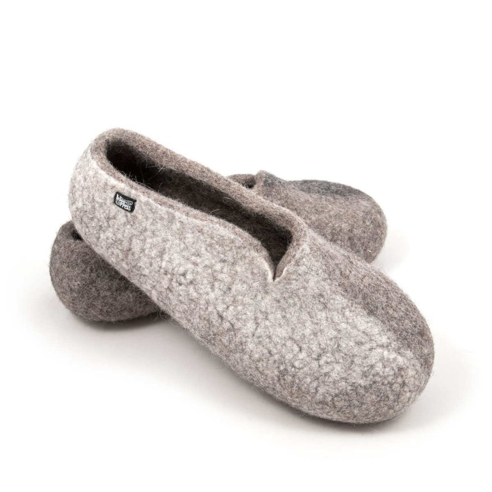 Winter - natural wool slippers from the SEASONS collection by Wooppers. The shoes are felted in grey wool with a stylish cut at the opening and different colors on the side of each shoe - white for the right and black for the left. The slippers are photographed with the right shoe over the left one.