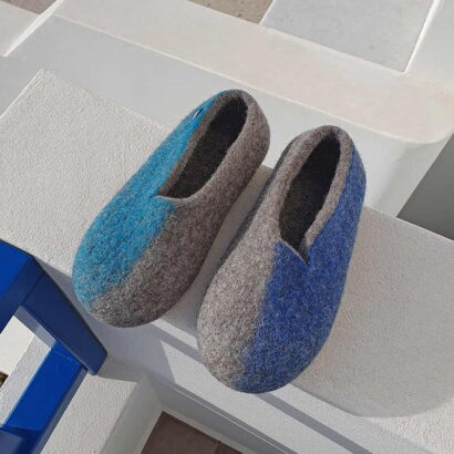A pair of wool slippers evoking the colors of summer in Greece - Blue and turquoise. The different colors are on the outer sides of each shoe. A new wavy cut at the opening makes the slippers very stylish.