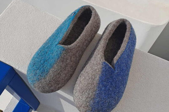 A pair of wool slippers evoking the colors of summer in Greece - Blue and turquoise. The different colors are on the outer sides of each shoe. A new wavy cut at the opening makes the slippers very stylish.
