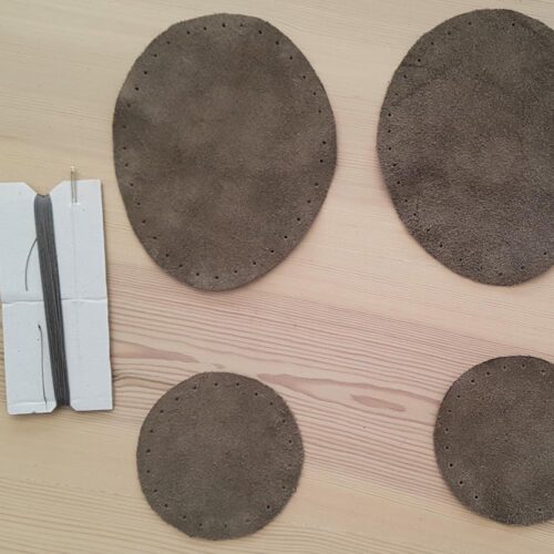 A kit of leather patches, thread and needle to be used for strengthening the soles of wooppers slippers.