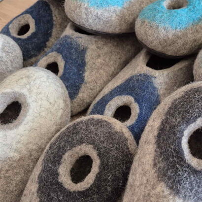 Several pairs of wool slippers for summer from the OMICRON collection by Wooppers. The slippers have a round hole at the front for extra ventilation.