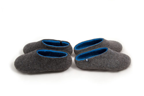 Two pairs of wool house slippers Grey with blue interior. Seen from the side the pair on the right has a low cut at the back and the pair on the left is closed-back. Felt wool slippers by Wooppers.