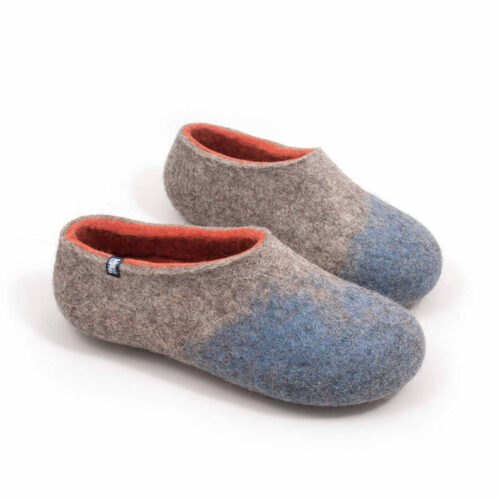 Seen from a slightly elevated angle, a pair of comfy wool slippers (slip-on, closed-back, low-cut ankle, no stitches, closed toe cups). Their color is mottled grey with pale blue in the area of the toes and burned orange on the inside.