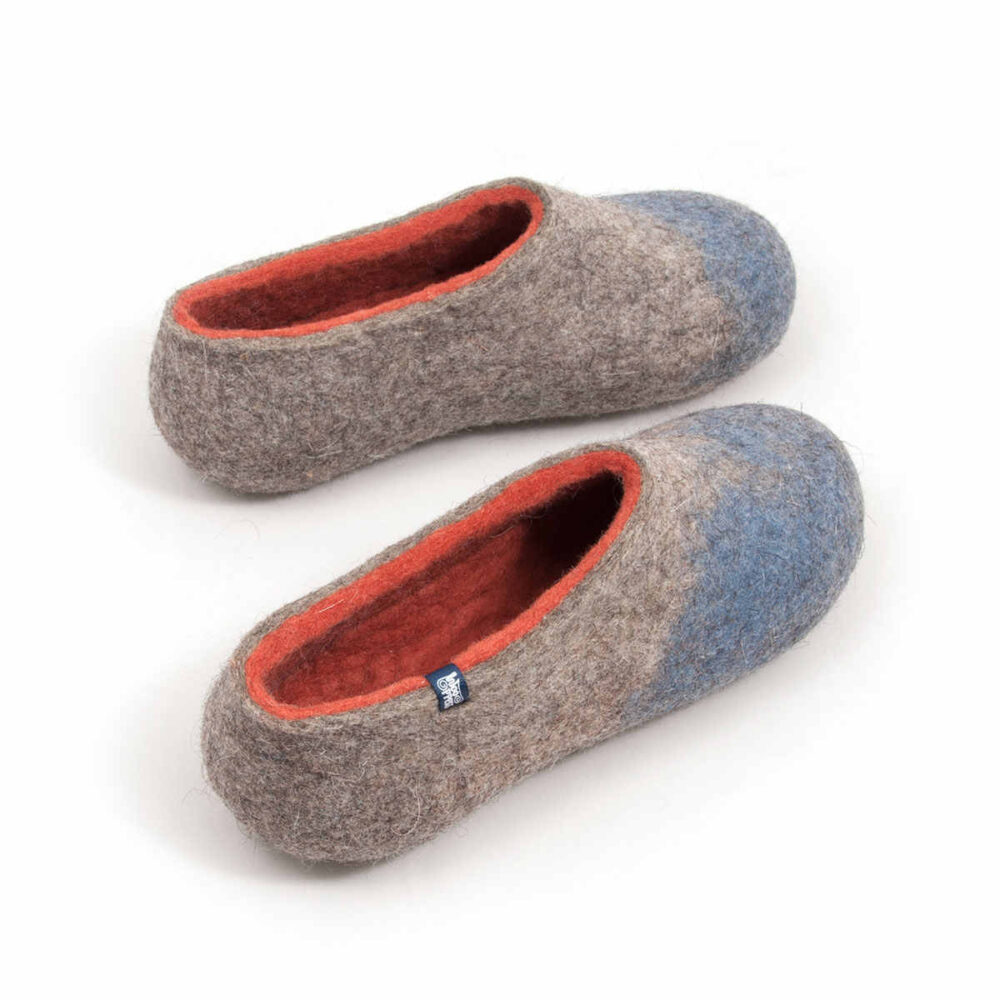 AMIGOS stone blue natural orange -e A pair of comfy wool slippers (slip-on, closed-back, low-cut ankle, no stitches, closed toe cups). Their color is mottled grey with pale blue in the area of the toes and burned orange on the inside. The pair is seen from a slightly elevated angle and from the back so the interior is more visible.