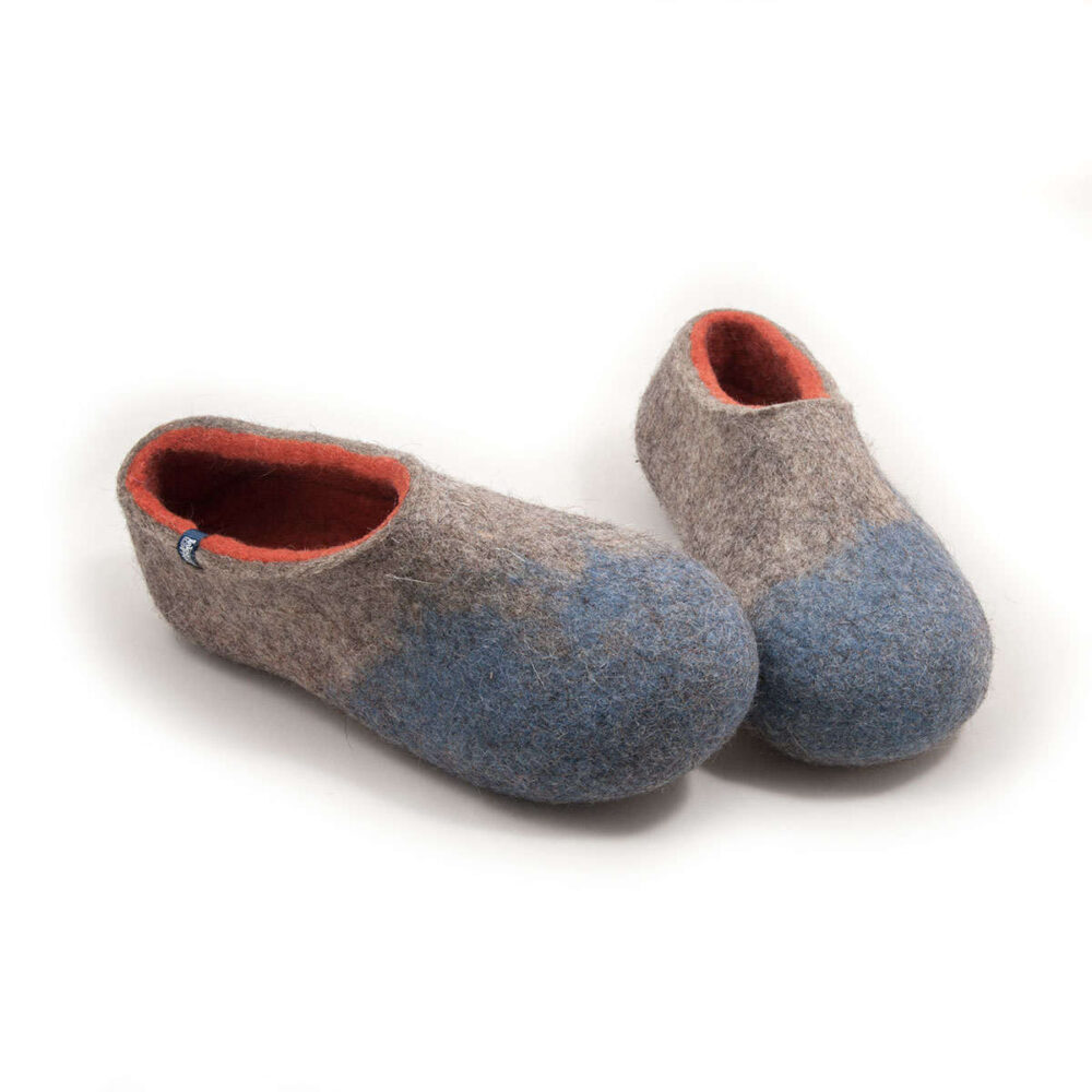 AMIGOS stone blue natural orange -g A pair of comfy wool slippers (slip-on, closed-back, low-cut ankle, no stitches, closed toe cups). Their color is mottled grey with pale blue in the area of the toes and burned orange on the inside. The pair is seen from a slightly elevated angle and from the front.
